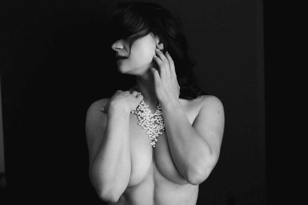 Black-and-white boudoir portrait of a woman with her hands framing her face, photographed at Heather Elizabeth’s Midtown Sacramento studio.