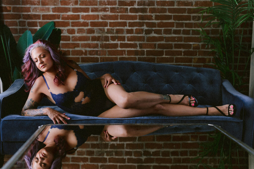 Woman reclining on a blue sofa during a Sacramento boudoir photography session